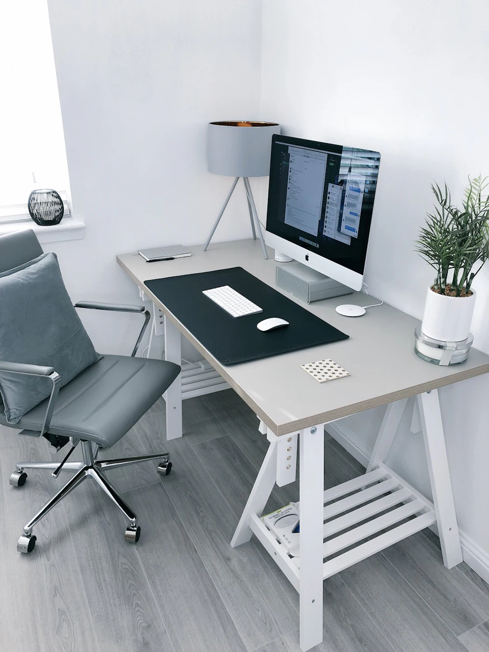 Gray leather office rolling armchair beside white wooden computer desk