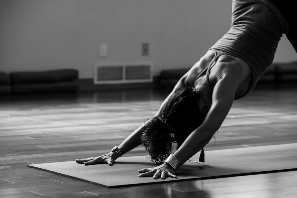 Woman in black tank top and black pants bending her body on floor