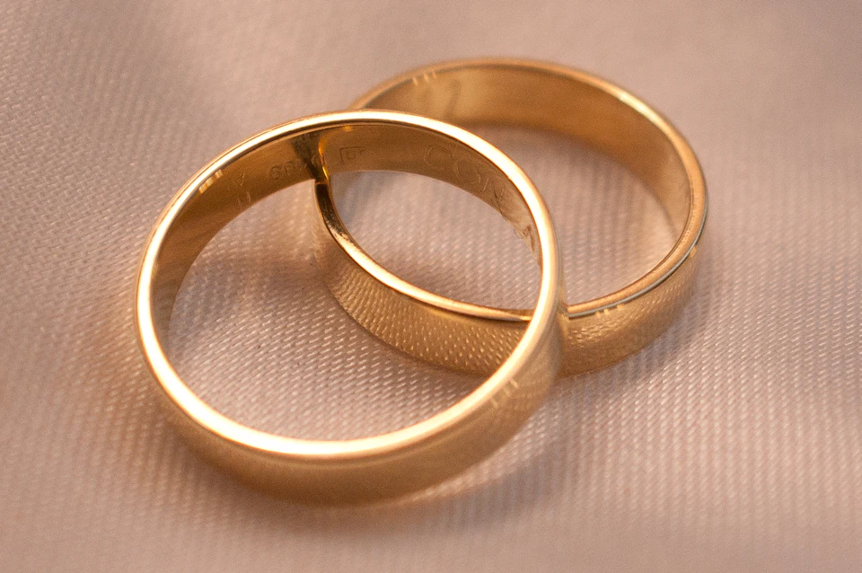 Two interlocking gold wedding bands on a textured cream fabric surface