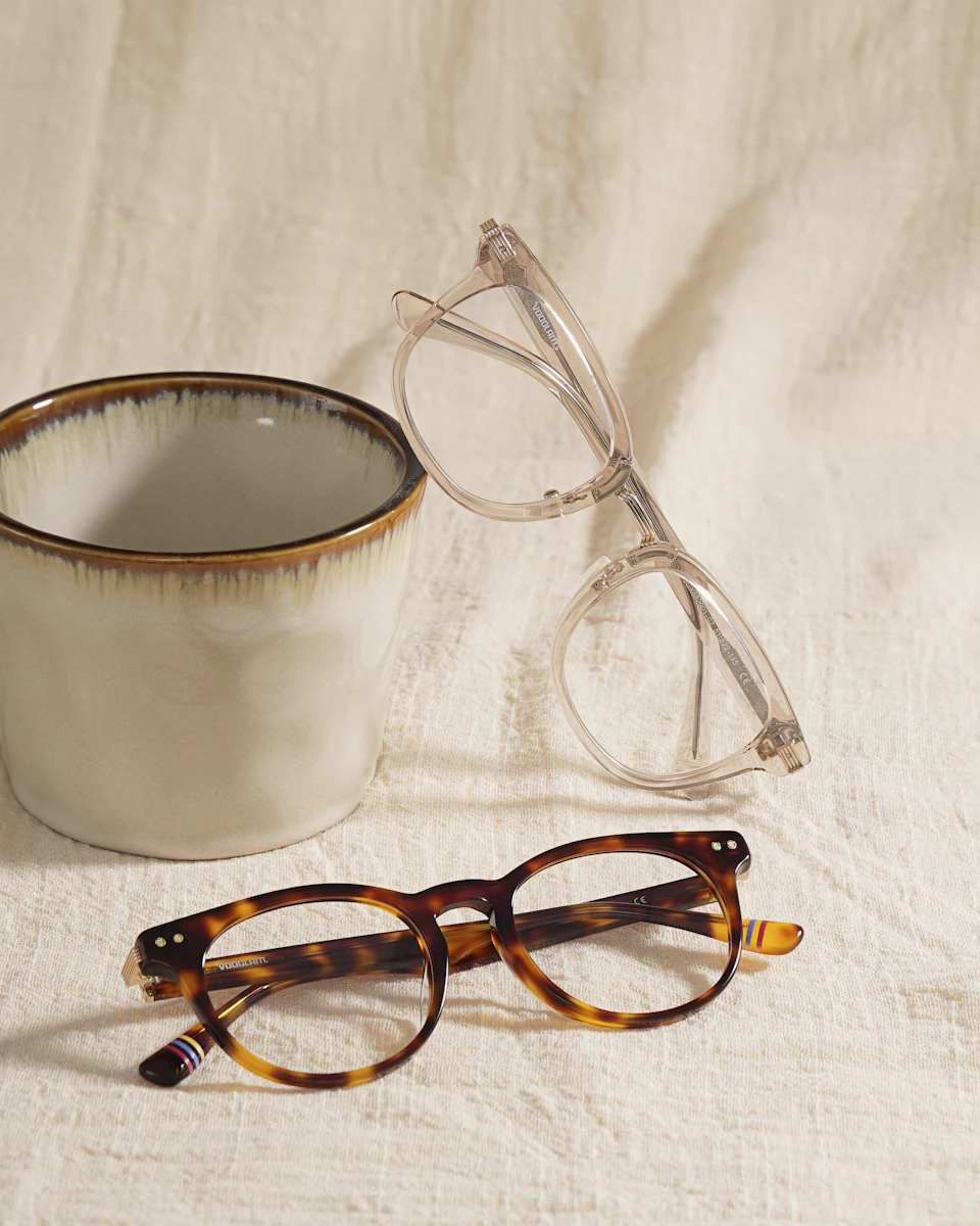 Two pairs of glasses and a cup on fabric