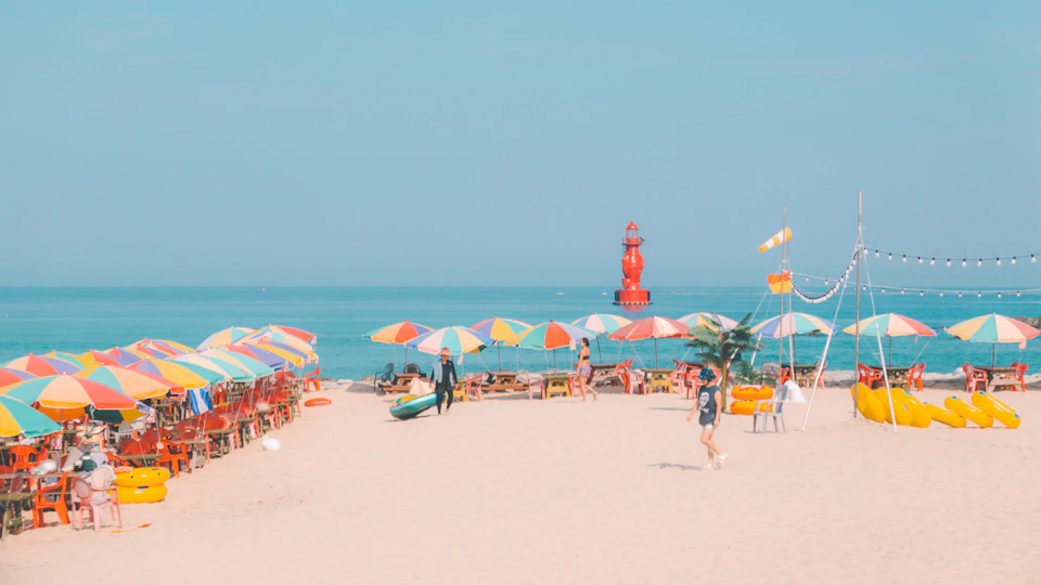 Colorful umbrellas line a sunny beach with ocean background