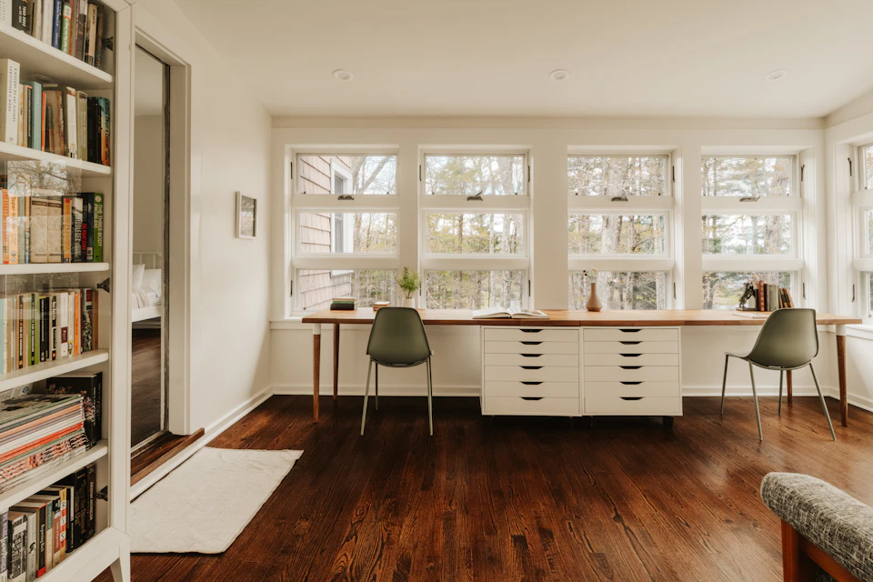 Bright room with bookshelves and two desks by windows