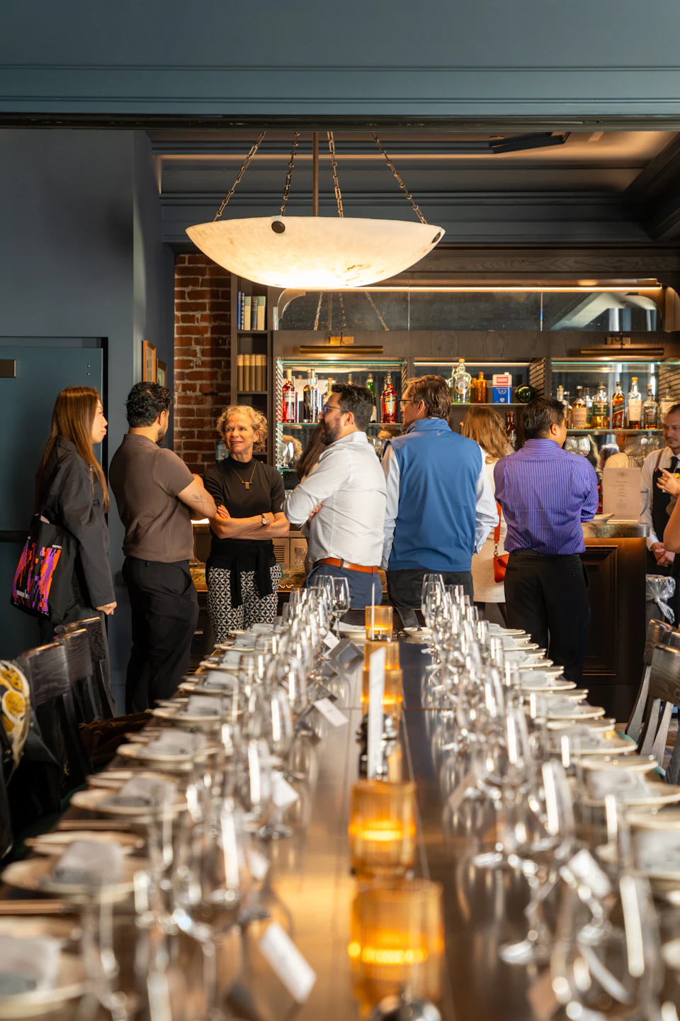 A group of people talking in a dimly lit restaurant with a long table